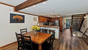 A modern kitchen with wooden cabinets, a central island, and a dining area with a wooden table and chairs. - Lakefront Haven:Lakefront Condo! Located in the Village! Community Spa & Pool! Private Dock! (Big Bear Lake)