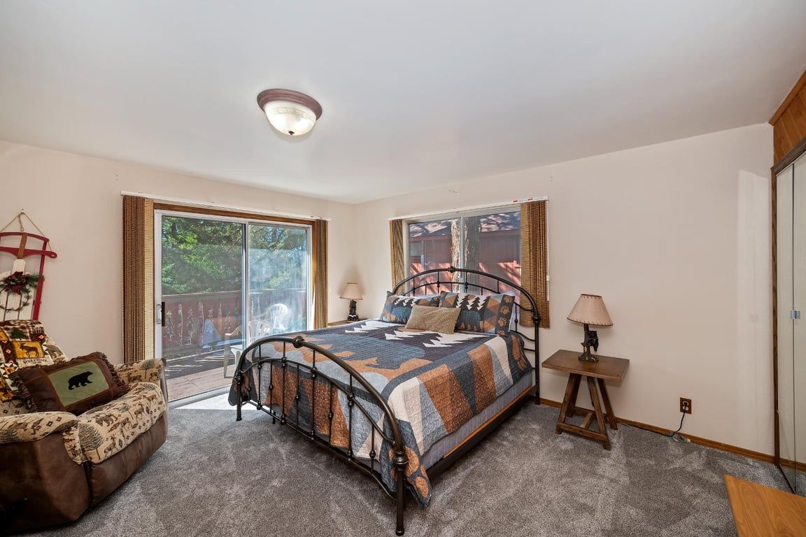 A bedroom with a bed, a chair, a lamp, and a sliding glass door leading to an outdoor area.