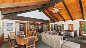 A cabin interior with a dining area, a sofa, a staircase, and a kitchen.