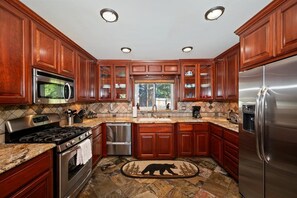 A kitchen with wooden cabinets, stainless steel appliances, and a bear-themed rug.
