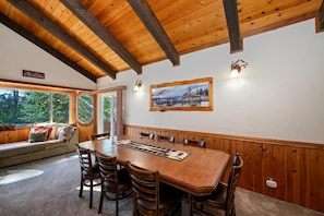 A dining area with a wooden table and chairs, a bench with cushions, and a framed picture on the wall.
