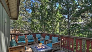 A wooden deck with outdoor seating and a fire feature.
