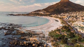 A coastal town with a prominent mountain, a beach, and residential buildings.