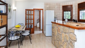Une cuisine compacte dotée d’un plan de travail en pierre, d’un réfrigérateur et d’un coin repas avec des chaises et une table.