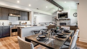 Een moderne keuken met donkerhouten kastjes, een roestvrijstalen fornuis en een groot kookeiland met barkrukken.