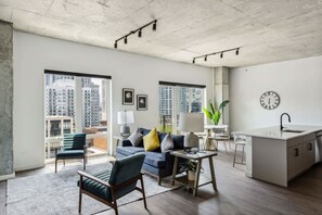 Een modern appartement met een woongedeelte, keuken en grote ramen met uitzicht over de stad.