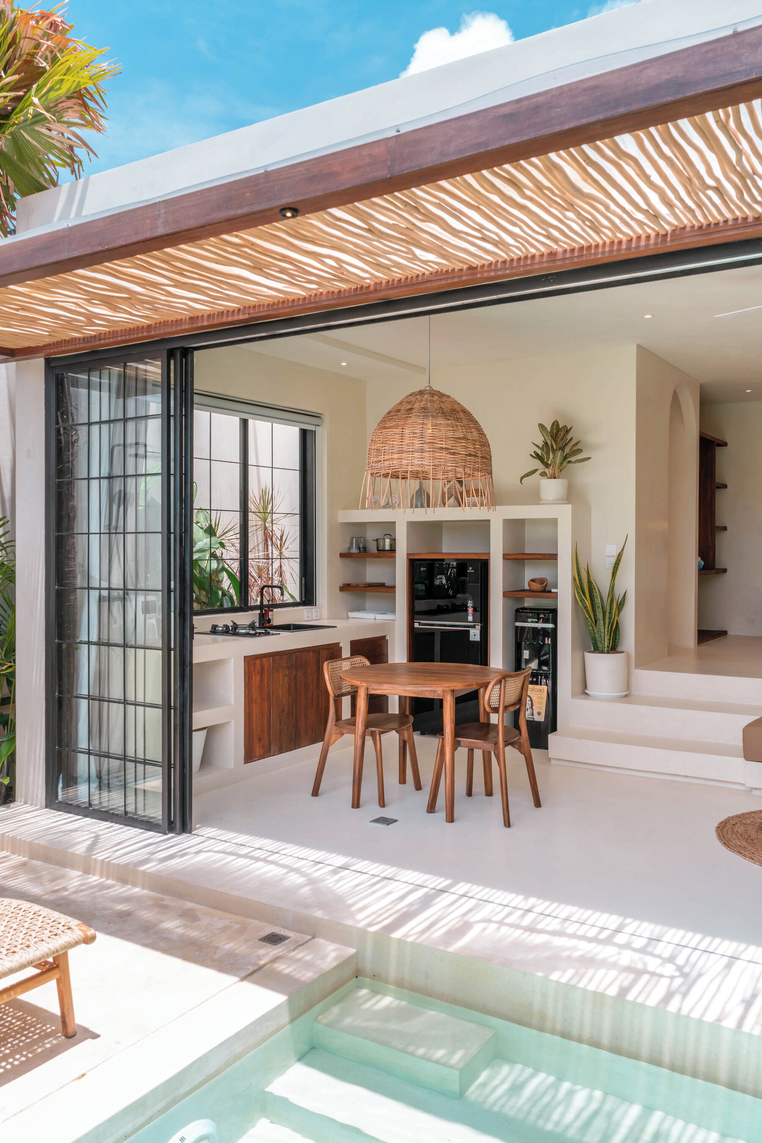 Une cuisine moderne dotée d’une grande fenêtre, de meubles en bois et d’un luminaire suspendu.