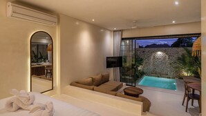 A modern hotel room with a large bed, a sofa, a small table, a TV, and a view of a swimming pool. - Casa Melosa - Charming and Intimate Villa Nestled in Umalas (Kerobokan)
