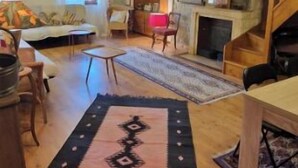 Un salon spacieux avec des poutres apparentes, une cheminée et un coin salon confortable.