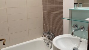 A bathroom with a bathtub, a sink, and a glass shelf with toiletries. - Family duplex overlooking the beach (Antibes)