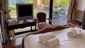 A hotel room with a bed, a desk with a television, and a chair. - Family duplex overlooking the beach (Antibes)