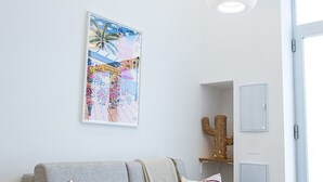 Una sala moderna con un sofá gris, dos lámparas colgantes, una decoración de cactus y una obra de arte enmarcada en la pared.