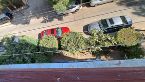 Vista aérea de una calle con coches aparcados y árboles.