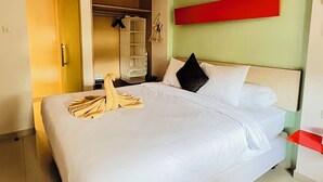A neatly made bed with white linens, a red accent wall, and a green accent wall. - Casa Kuta View 2 BR (Kuta)