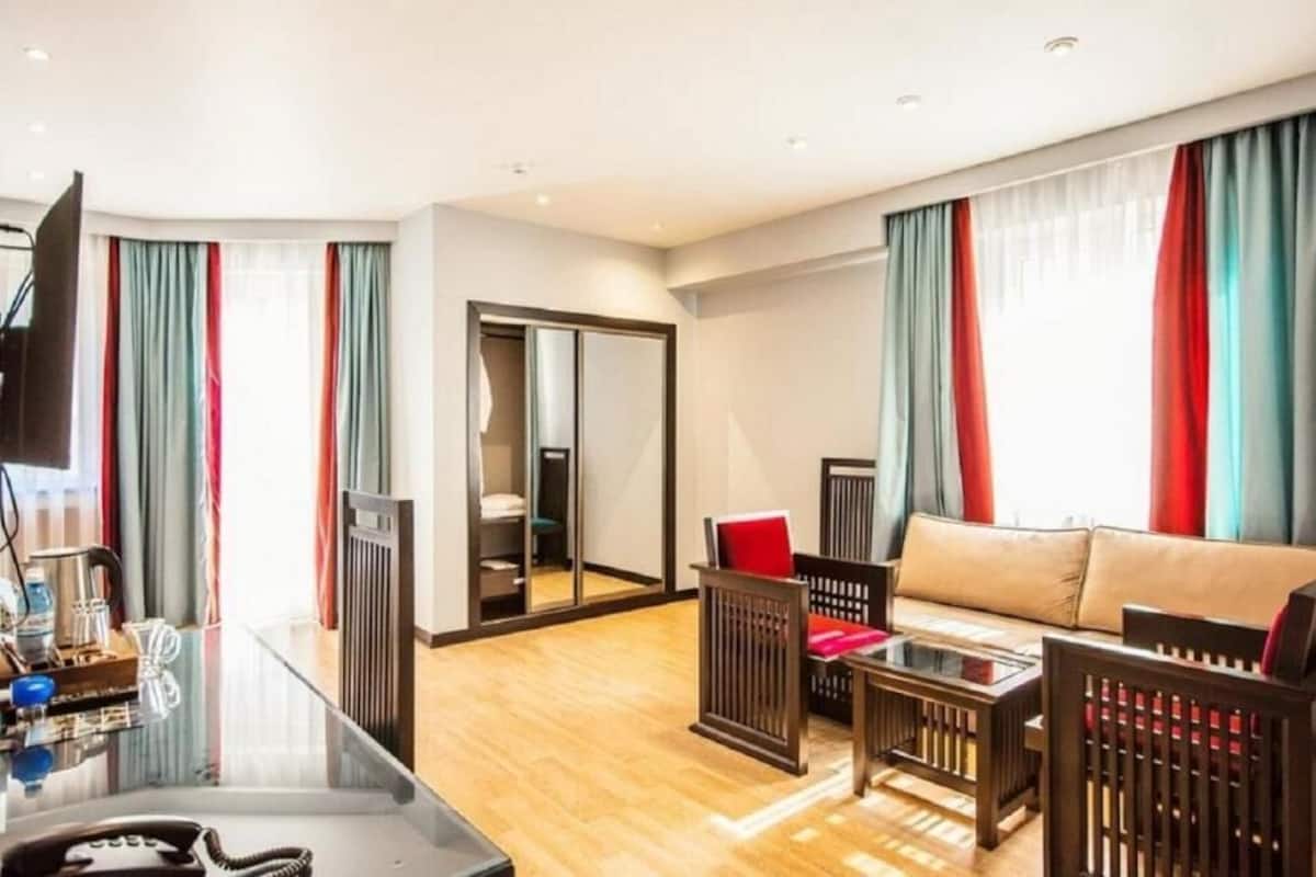 A modern hotel room with a sofa, a small table, a mirror, and a wardrobe.