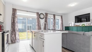Eine moderne Küche mit einer zentralen Kochinsel, einem grauen Sofa und einem grünen Schrank.