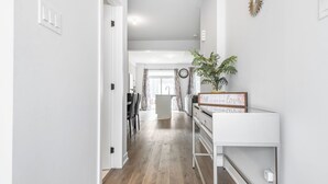 Ein Korridor mit Holzboden, weißer Wand und einer Pflanze auf einem Regal.