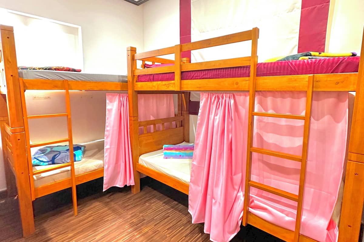 A bunk bed room with pink curtains and a wooden floor.
