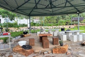 Une terrasse extérieure avec un sol en pierre, un espace salon couvert et un coin barbecue.