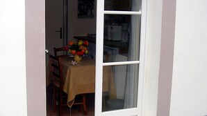 A dining area with a table set for two, a vase with flowers, and a window with curtains.