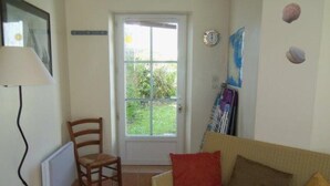 A living room with a sofa, a chair, a radiator, a door, and a window.