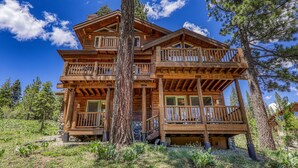A multi-story log cabin with a balcony on the second floor, surrounded by trees. - Horizon by Tahoe Getaways - Pet Friendly Tahoe Donner w Hot Tub (Truckee)