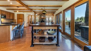 A spacious kitchen with wooden beams, a central island, and a large window overlooking a deck. - Horizon by Tahoe Getaways - Pet Friendly Tahoe Donner w Hot Tub (Truckee)