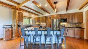 A spacious kitchen with wooden cabinets, a central island with bar stools, and a stainless steel refrigerator. - Horizon by Tahoe Getaways - Pet Friendly Tahoe Donner w Hot Tub (Truckee)