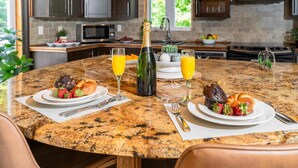 A kitchen with granite countertops, dark wooden cabinets, a stainless steel range hood, and a window with a view of greenery. - Cozy chalet with Pool and Spa (Grenville-sur-la-Rouge)