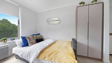 A bedroom with a bed, a wardrobe, a radiator, and a window with a view of trees.