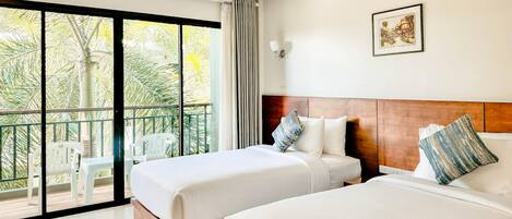 A hotel room with two beds, a balcony with chairs, and a large window with curtains.