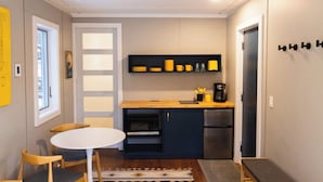 A compact kitchen with a white table and chairs, a built-in oven, and a coffee maker.