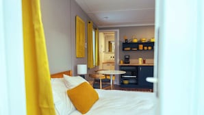 A hotel room with a bed, a small table, and a kitchenette.