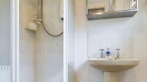 A bathroom with a shower, a sink, and a mirror. - Two Bedroom Chalet, in Penstowe Park Near Bude Cornwall close to Beaches. (Kilkhampton)