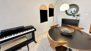 A modern dining area with a piano, a round table, and a mirror on the wall. - Mylos home (Ierapetra)