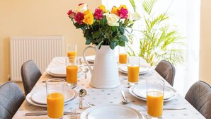 Et spisebord dækket med tallerkener, glas med appelsinjuice og en vase med blomster.