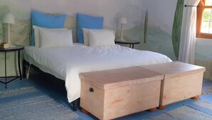 A bed with white bedding, two blue pillows, and two wooden nightstands with lamps. - Gecko Pet-friendly cottage on Fynbos Garden Retreat (Franschhoek)
