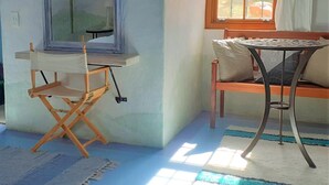 A room with a wooden bench, a small round table, and a director's chair. - Gecko Pet-friendly cottage on Fynbos Garden Retreat (Franschhoek)