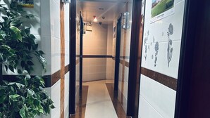 Un pasillo con paredes de azulejos, piso de mármol y una planta en maceta.