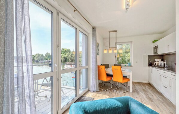 A modern kitchen with white cabinets and a dining area with orange chairs.