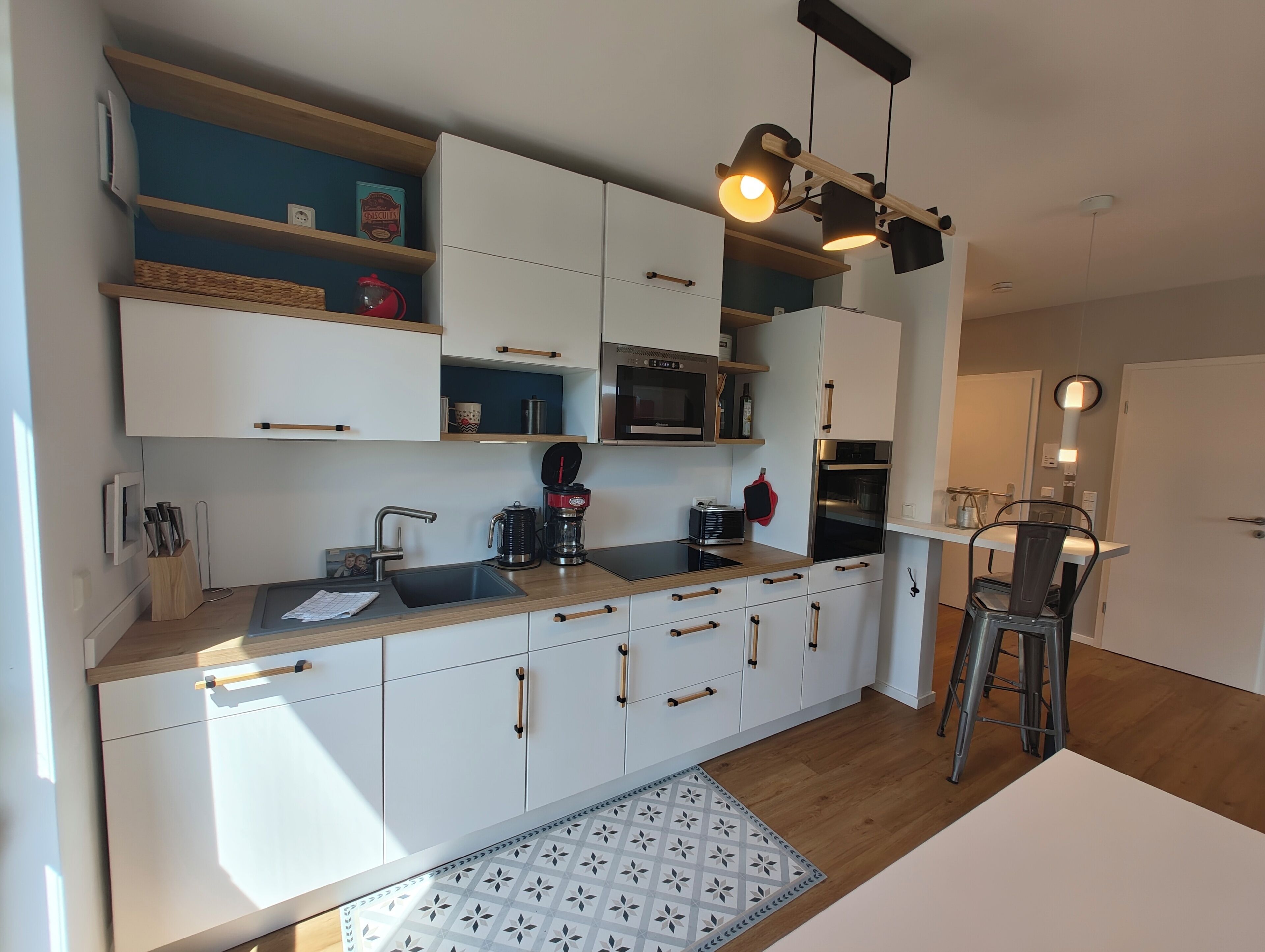 A modern kitchen with white cabinets, a wooden countertop, a coffee maker, and a microwave.