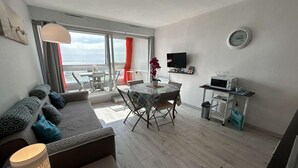 Ein modernes Wohnzimmer mit Sofa, Esstisch und Küchenzeile inklusive Mikrowelle.