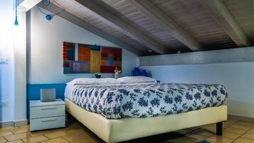 A bedroom with a bed, a nightstand, a wall with colorful artwork, and a ceiling with exposed beams.