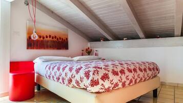 Ein Schlafzimmer mit einem Bett, einem roten Sessel, einem Gemälde und einem gefliesten Boden.