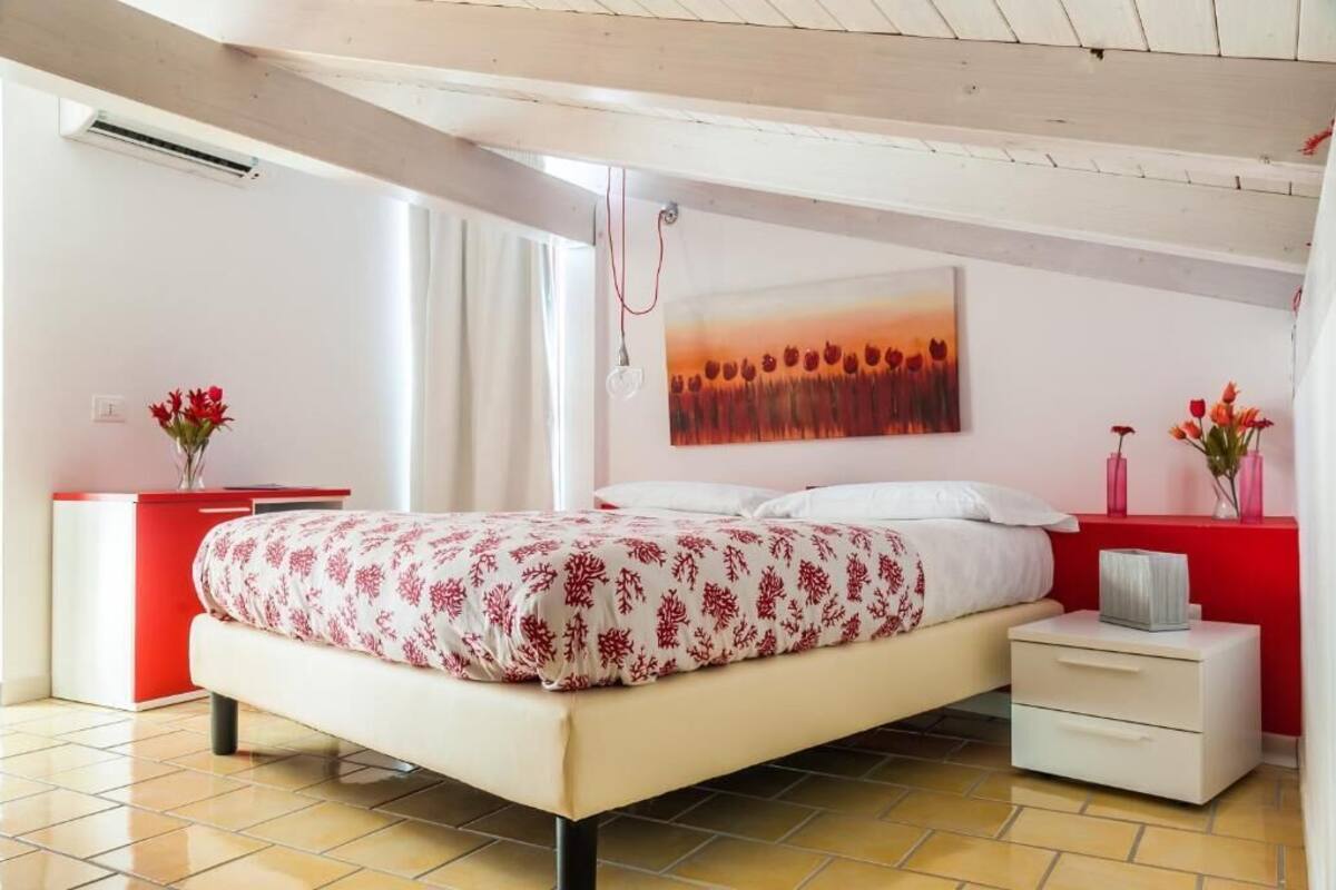 A bedroom with a bed, nightstands, a painting, and a window.