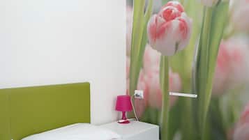 Ein Schlafzimmer mit einem grünen Kopfteil, weißer Bettwäsche und einer pinkfarbenen Lampe auf einem Nachttisch.