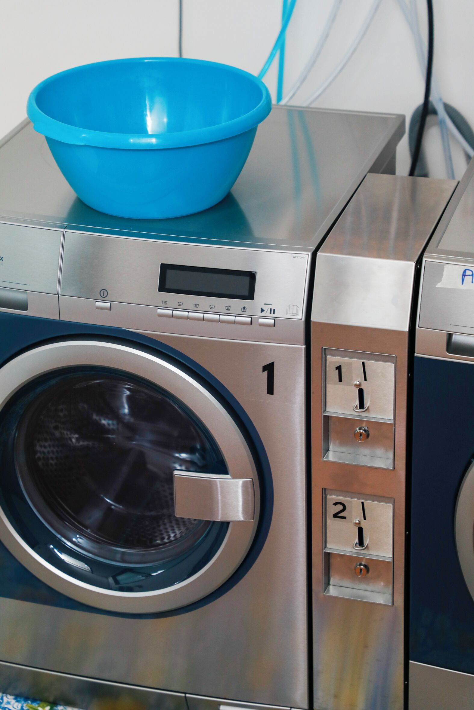A front view of a modern, stainless steel washing machine with a digital display and control panel.