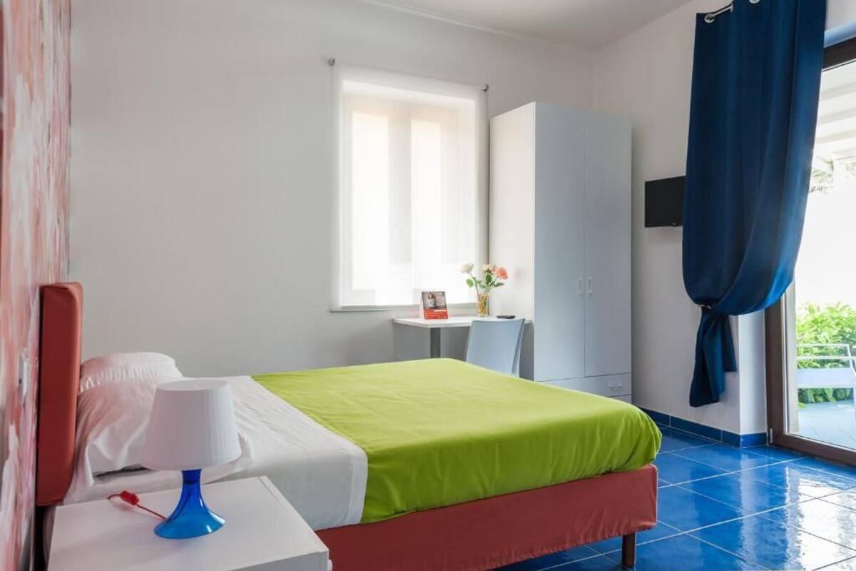 A hotel room with a bed, a desk, a chair, a TV, and a window with curtains.
