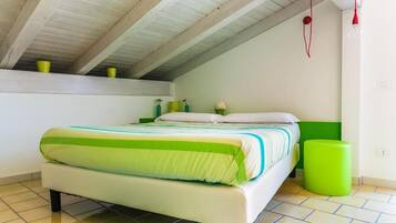 Un dormitorio con una cama, un taburete verde y una pequeña planta verde sobre una estantería.