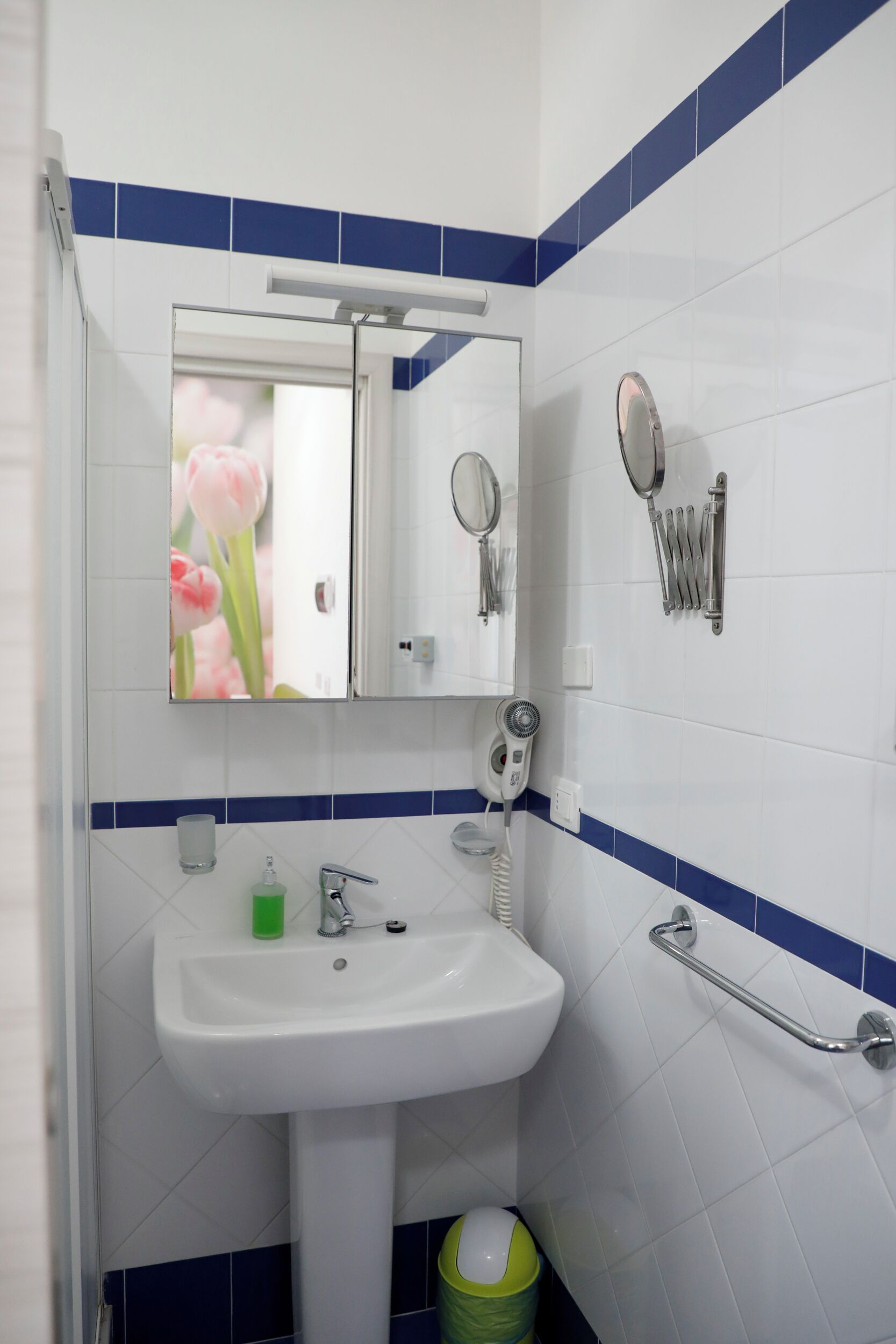 Un baño con lavamanos blanco, un espejo y un secador de manos.